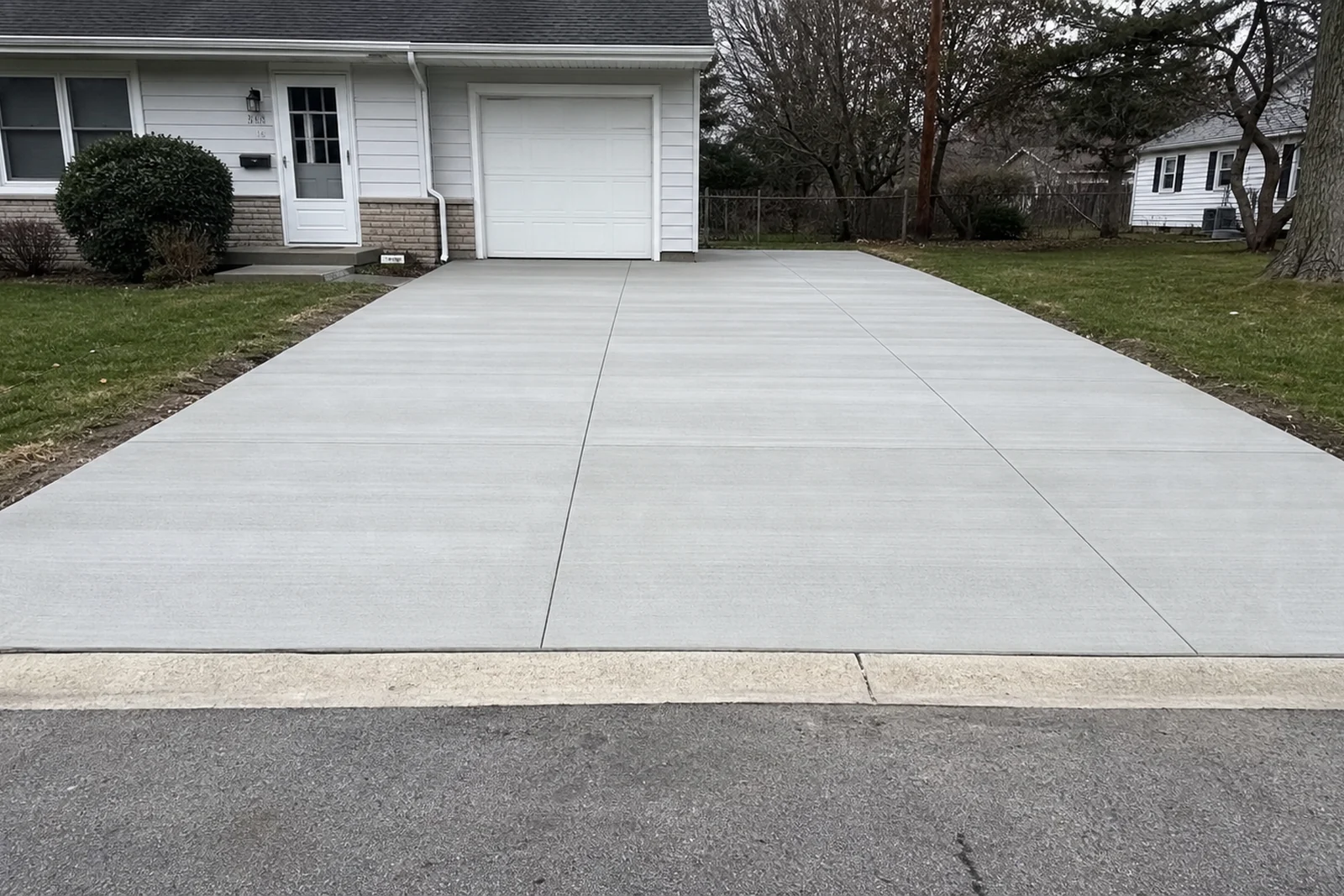 New broom-finished concrete driveway in Elkhart Indiana with clean control joints and curb approach